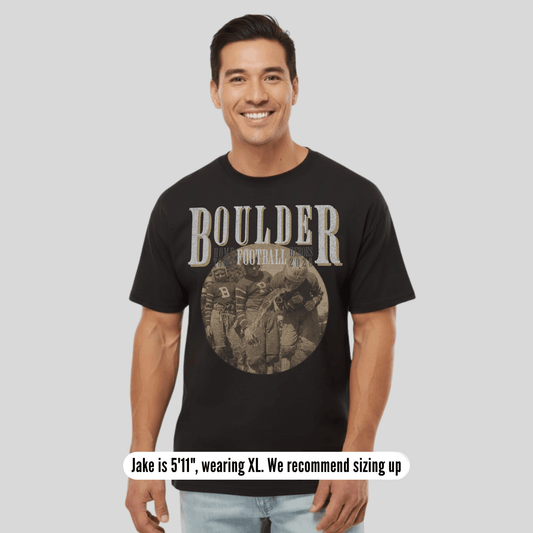 Man wearing a black t-shirt with 'BOULDER' printed on it, standing against a plain background.