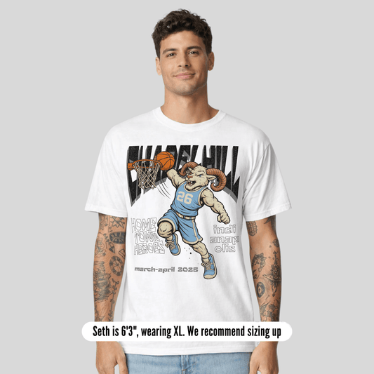 Man wearing a white t-shirt with a graphic design of a ram playing basketball, on a plain background.