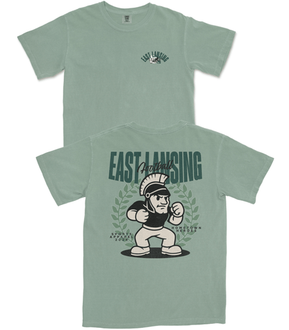 Green t-shirt with 'East Lansing' and cartoon character design on a white background