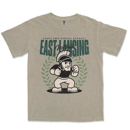 Beige t-shirt with 'East Lansing Football' graphic design on a white background