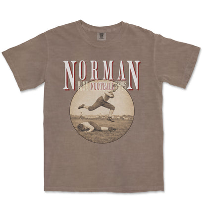 Brown t-shirt with vintage football graphic and 'Norman' text on a white background