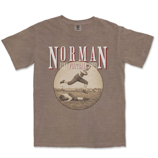 Brown t-shirt with vintage football graphic and 'Norman' text on a white background
