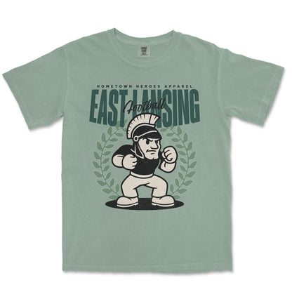 Green t-shirt with cartoon Spartan and 'East Lansing' text on a white background