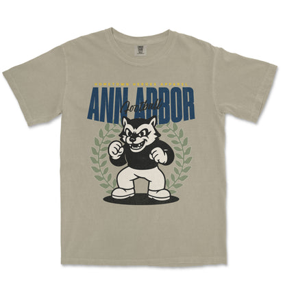 Beige t-shirt with a graphic of a cartoon dog and 'Ann Arbor' text on a white background