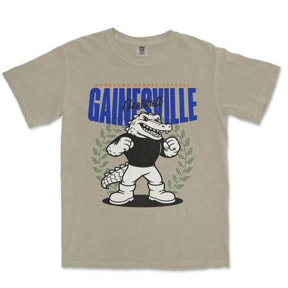 Beige t-shirt with cartoon alligator graphic and 'Gainesville' text on a white background