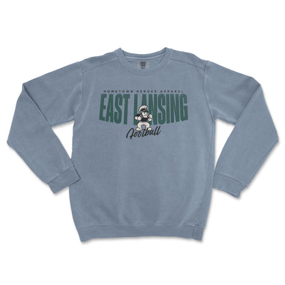 Blue sweatshirt with 'East Lansing Football' text and graphic on a white background