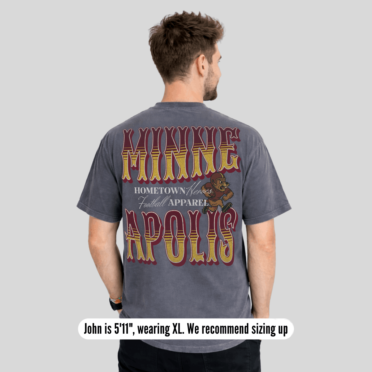 Man wearing a gray t-shirt with 'Minneapolis' text and bear graphic on the back, on a light gray background.
