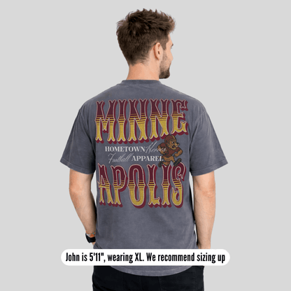 Man wearing a gray t-shirt with 'Minneapolis' text and bear graphic on the back, on a light gray background.
