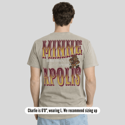 Person wearing a t-shirt with 'Minneapolis' text and graphic on the back, standing against a plain background.