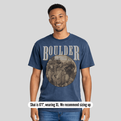 Man wearing a blue t-shirt with 'BOULDER' printed on it, standing against a plain background.