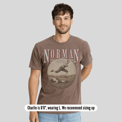 Man wearing a brown t-shirt with 'Norman Football' design on a gray background