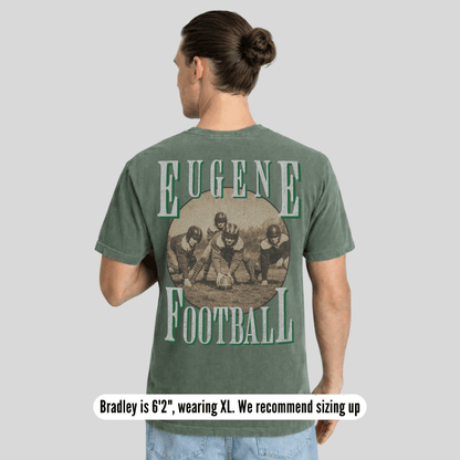 Person wearing a green t-shirt with 'Eugene Football' print on the back, standing against a gray background.