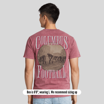 Person wearing a maroon t-shirt with 'Columbus Football' design on the back, standing against a plain background.