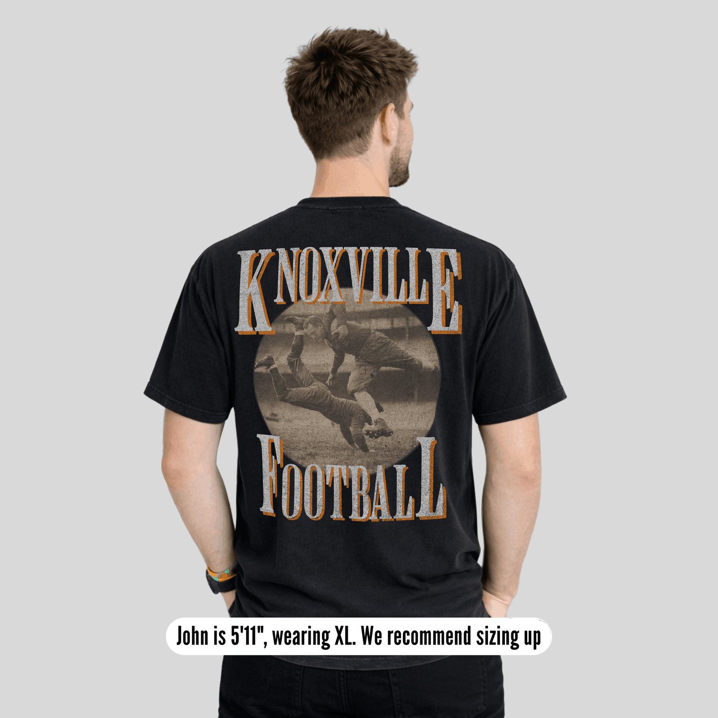 Man wearing a black t-shirt with 'Knoxville Football' design on the back, on a plain background.
