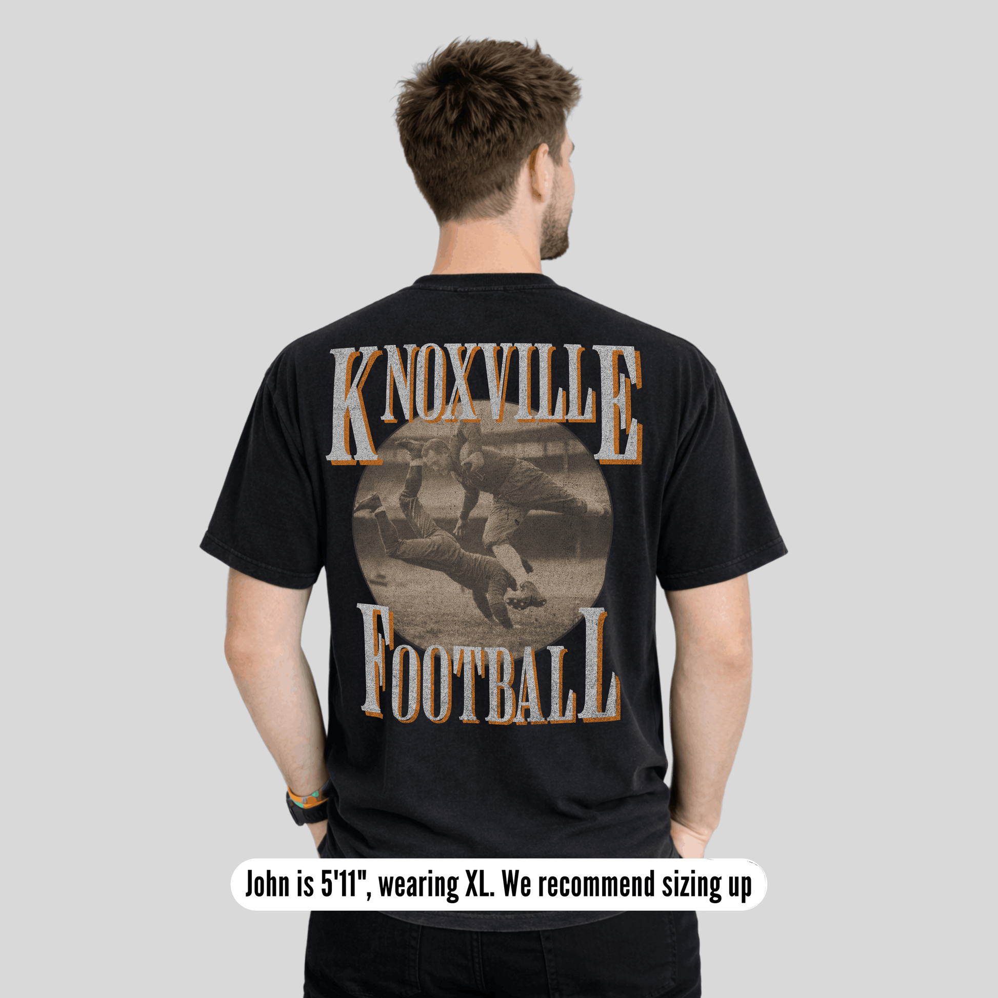 Man wearing a black t-shirt with 'Knoxville Football' design on the back, on a plain background.