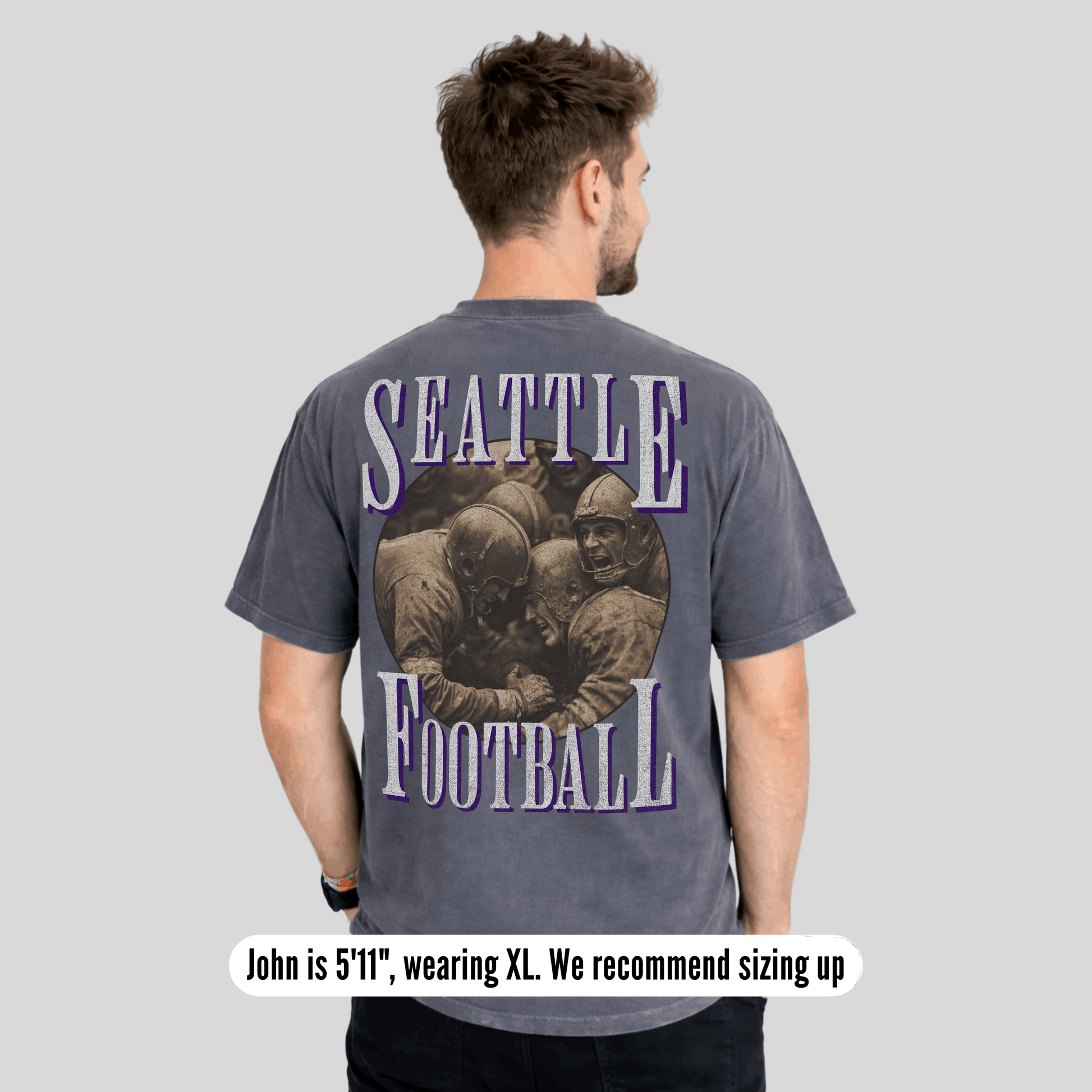 Man wearing a gray t-shirt with 'Seattle Football' design on the back, on a light gray background.