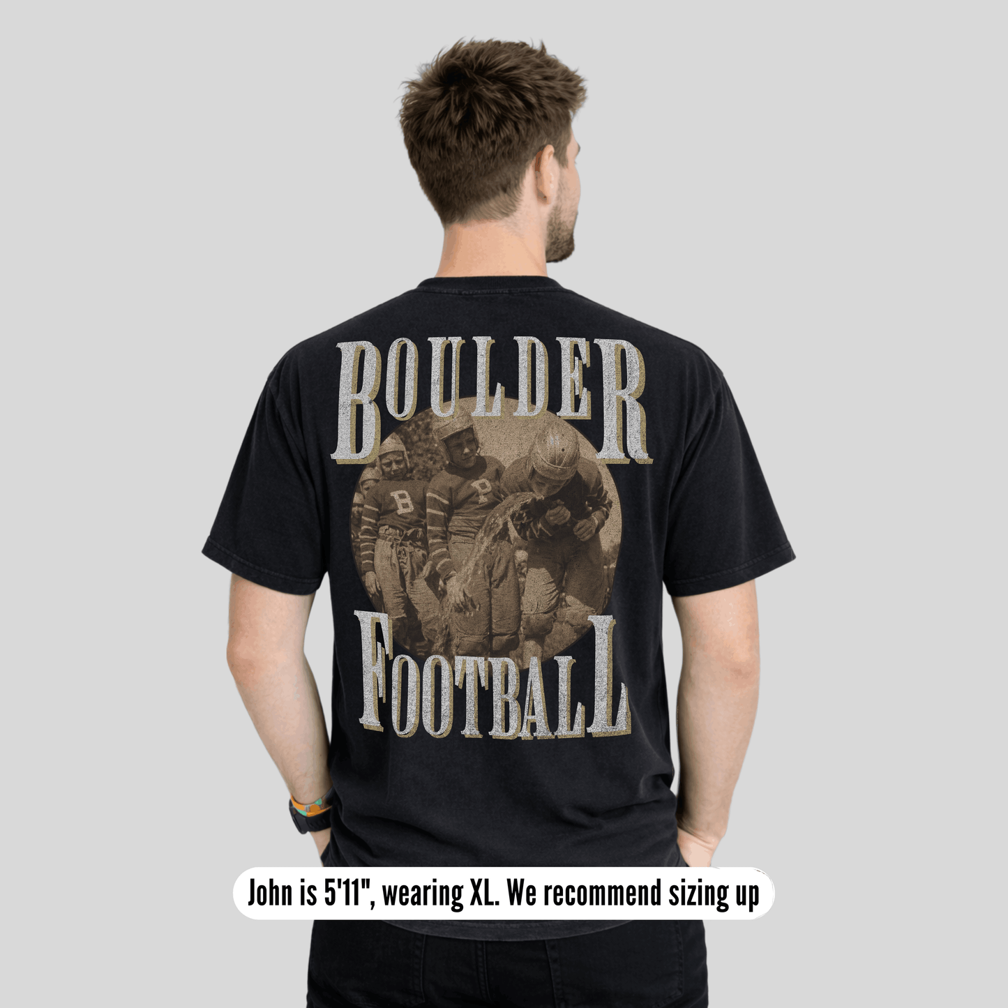 Man wearing a black t-shirt with 'Boulder Football' design on the back, standing against a plain background.