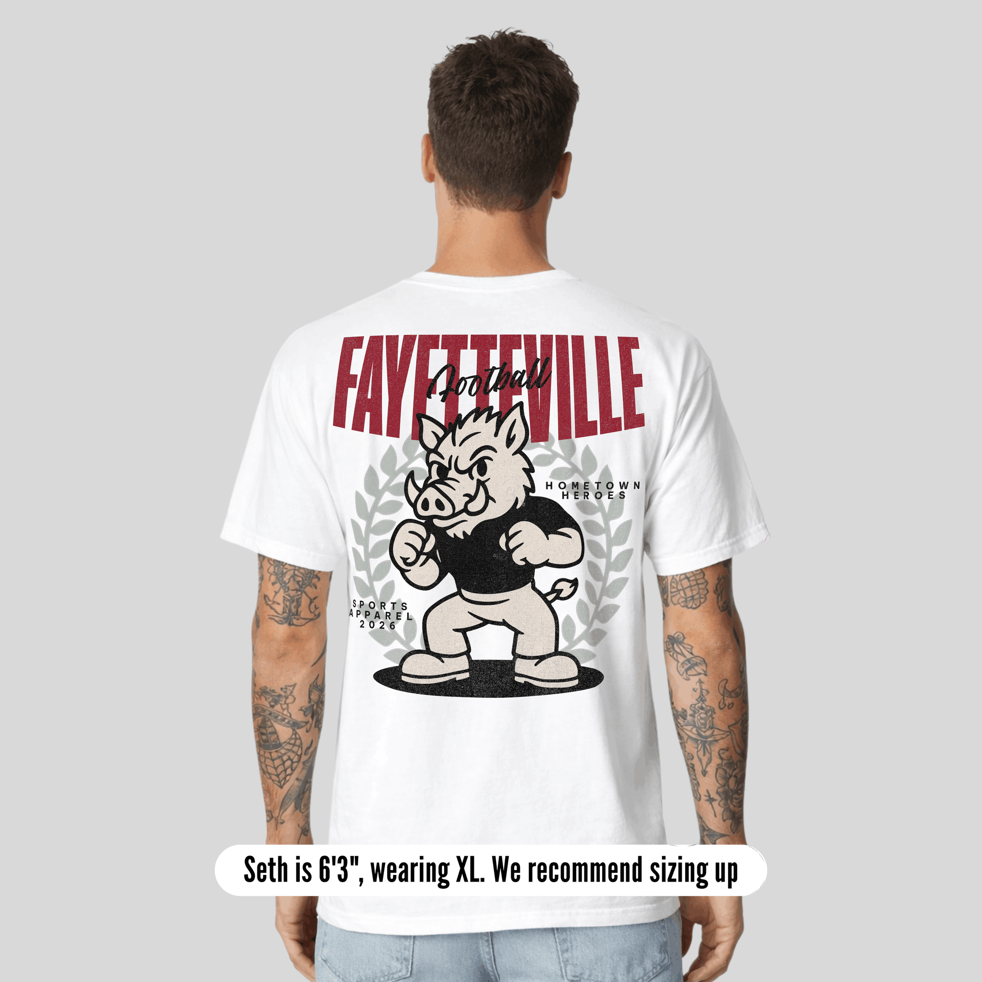 Person wearing a white t-shirt with 'Fayetteville' and a cartoon boar design on the back.