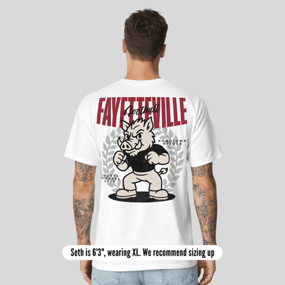 Person wearing a white t-shirt with 'Fayetteville' and a cartoon boar design on the back.