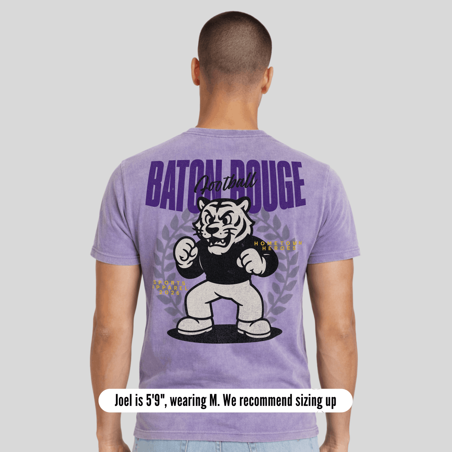 Person wearing a purple t-shirt with a graphic and text on the back, on a light gray background.