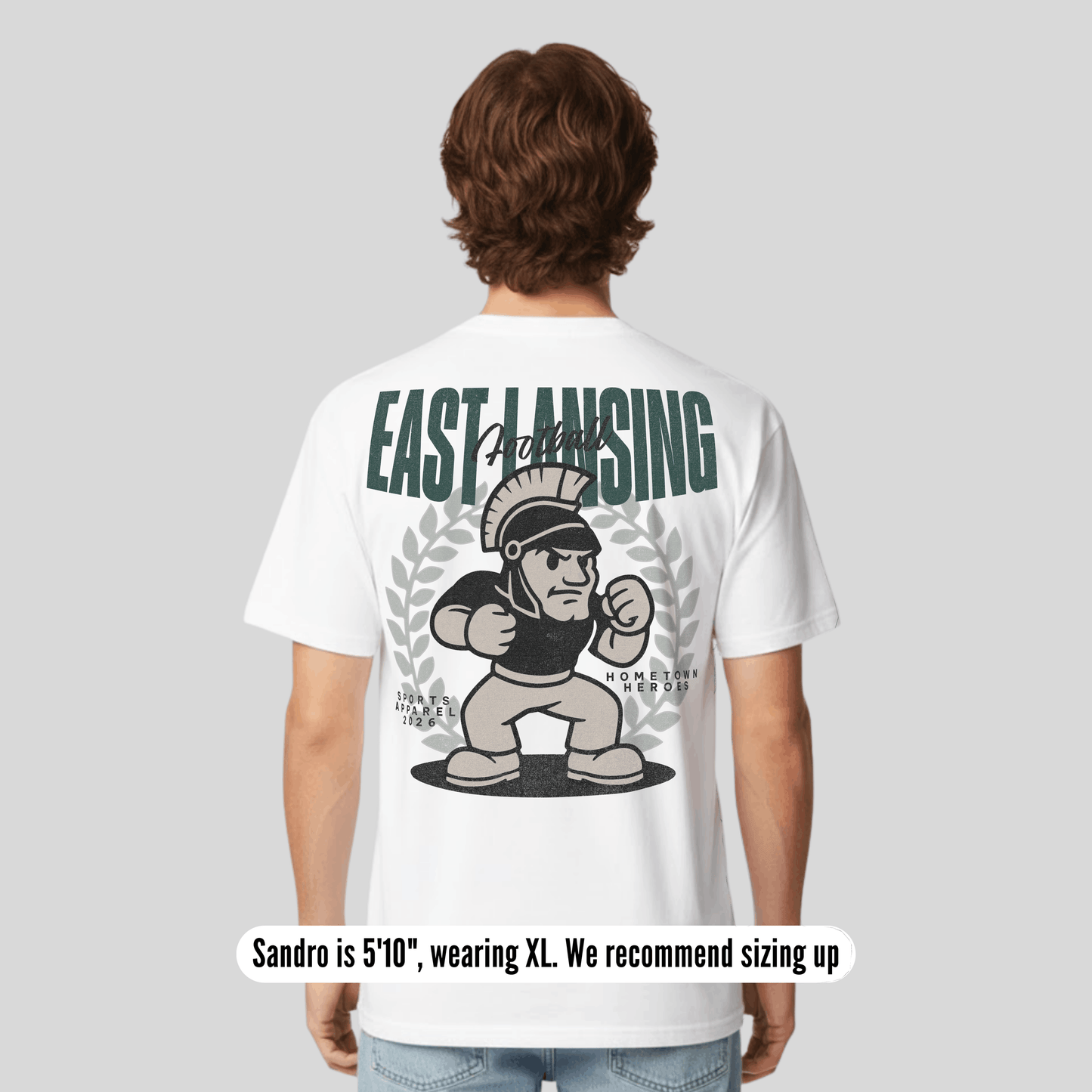 Person wearing a white t-shirt with 'East Lansing' and a Spartan graphic on the back.