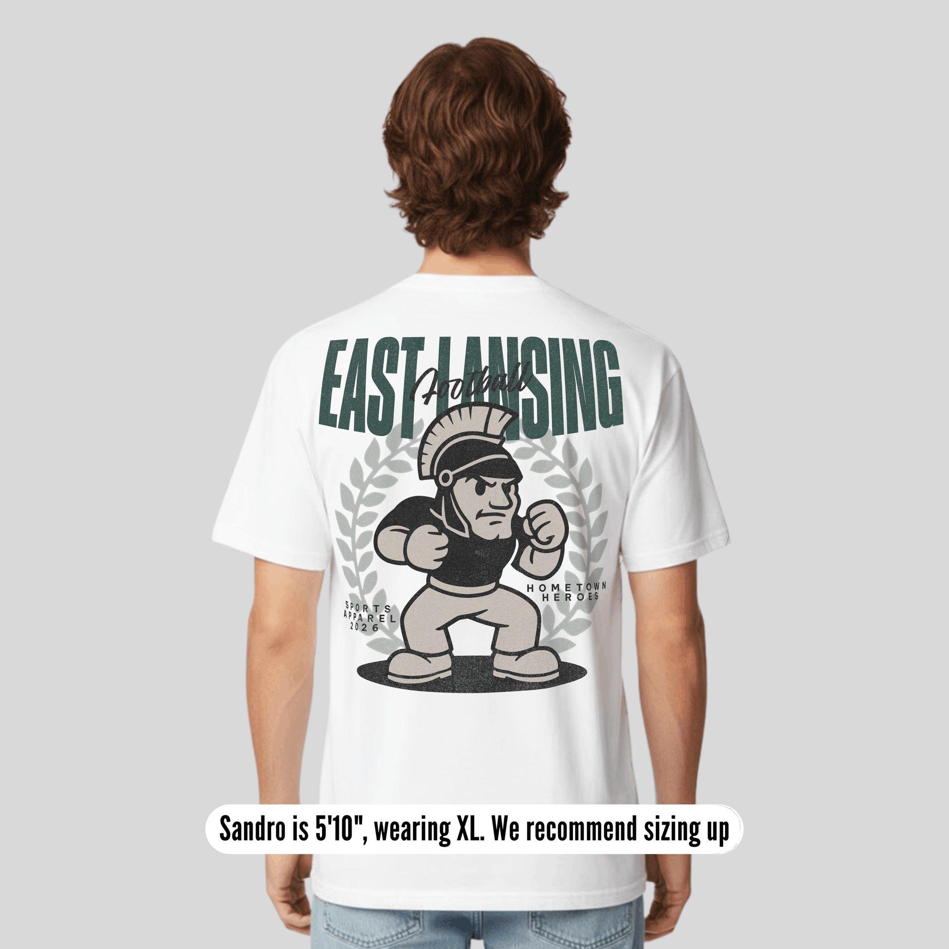 Person wearing a white t-shirt with 'East Lansing' and a Spartan graphic on the back.