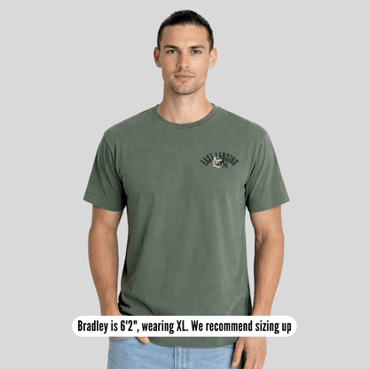 Man wearing a green t-shirt with a logo on a gray background