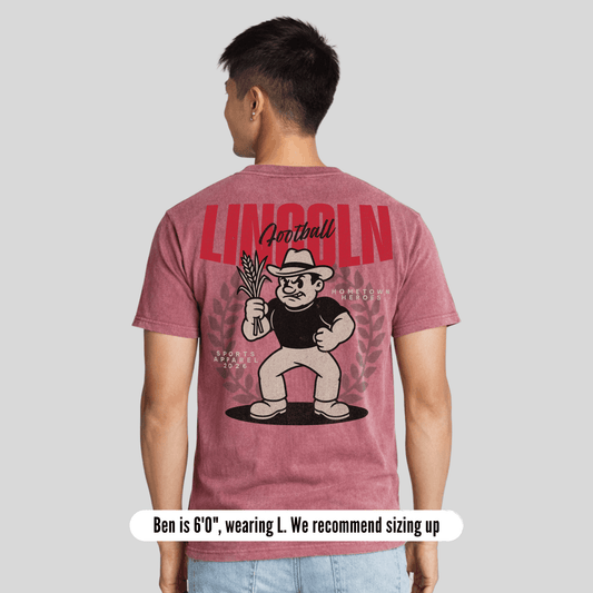 Person wearing a maroon t-shirt with a graphic design on the back, standing against a plain background.