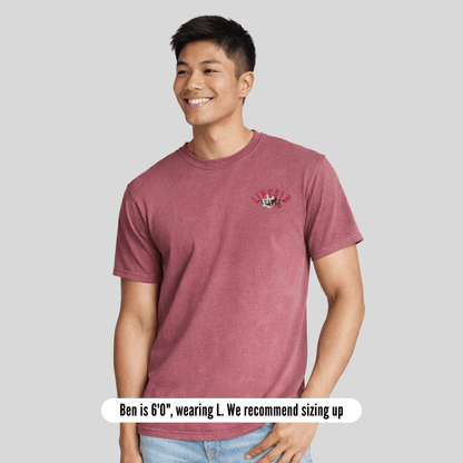 Man wearing a maroon t-shirt with a small graphic on a gray background