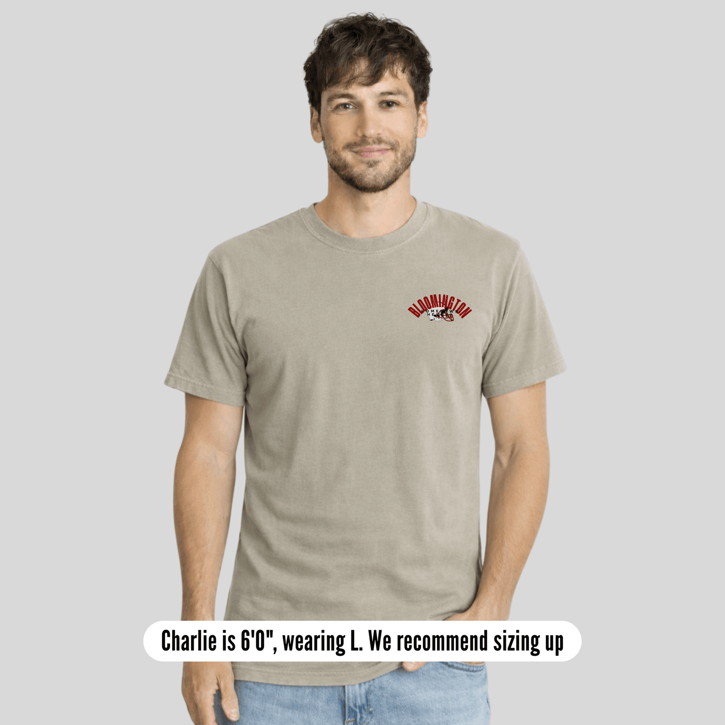 Man wearing a beige t-shirt with a logo on a gray background