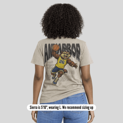 Person wearing a t-shirt with a graphic design on the back, standing against a plain background.