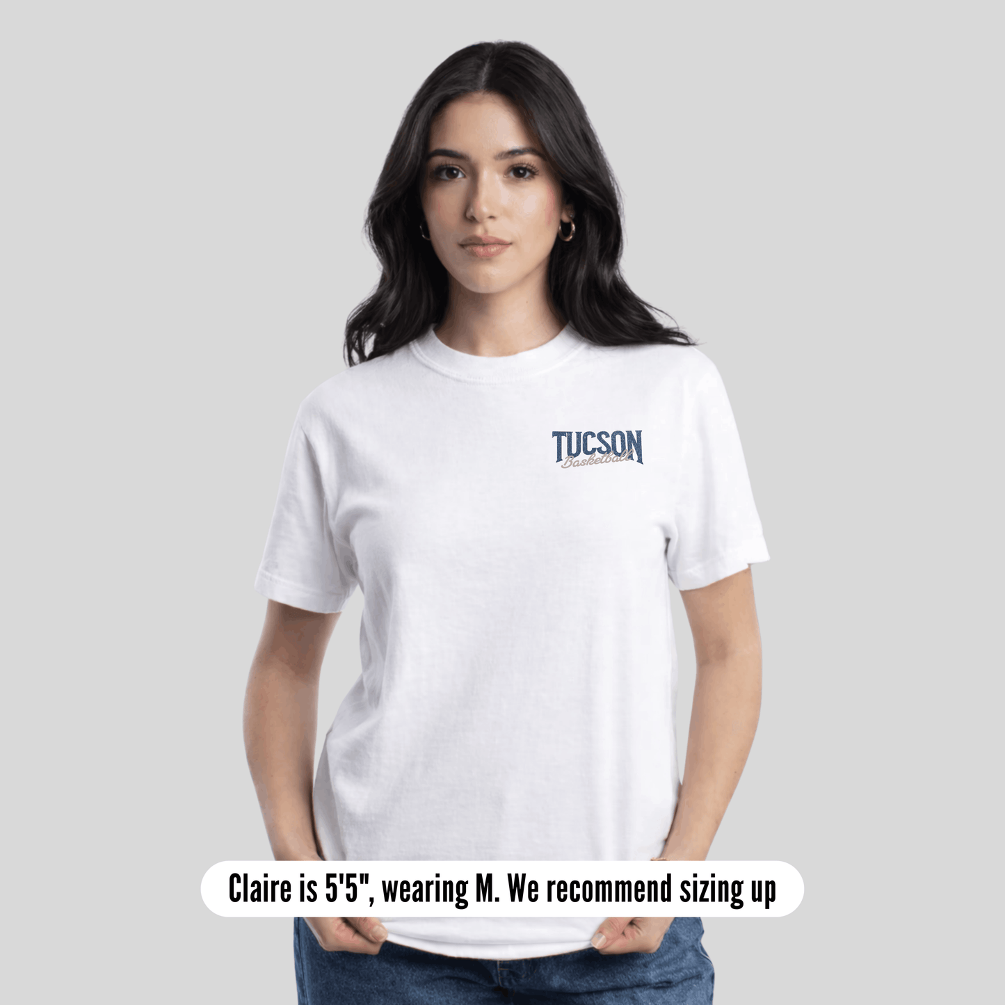 Woman wearing a white t-shirt with a small graphic on a plain background