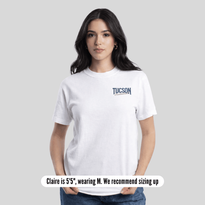 Woman wearing a white t-shirt with a small graphic on a plain background