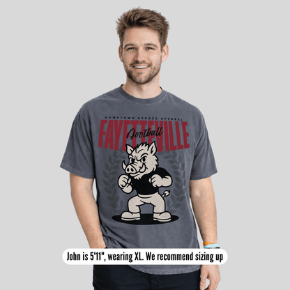 Man wearing a gray t-shirt with a graphic design and text, standing against a plain background.