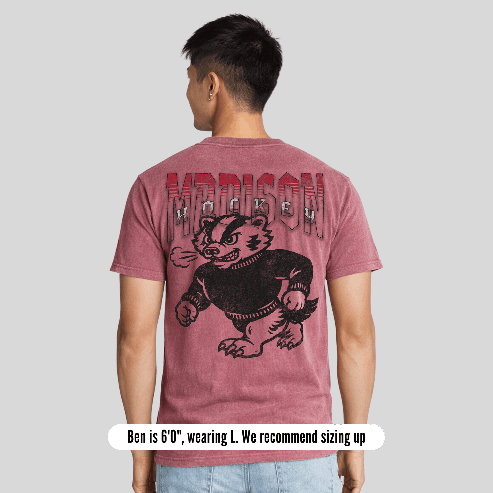 Person wearing a maroon t-shirt with 'Madison' and a badger graphic on the back, on a plain background.