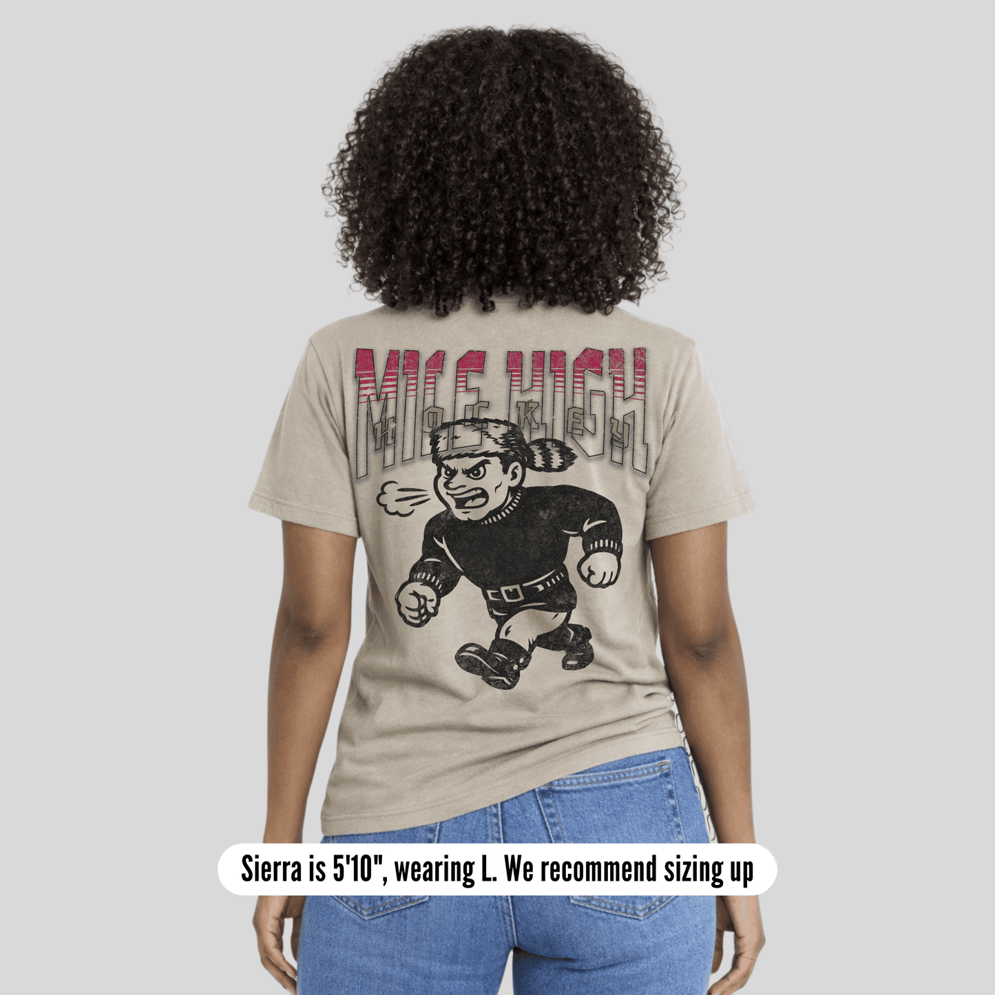 Person wearing a beige t-shirt with graphic design and text on the back, standing against a plain background.