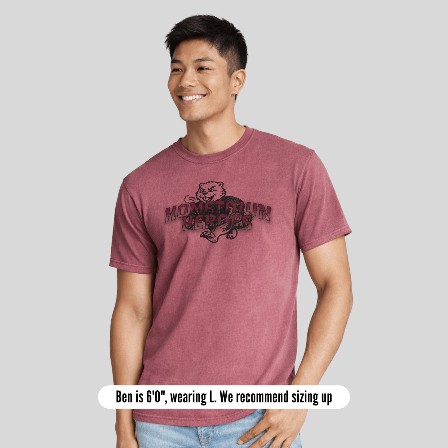 Person wearing a maroon t-shirt with a graphic design on a gray background